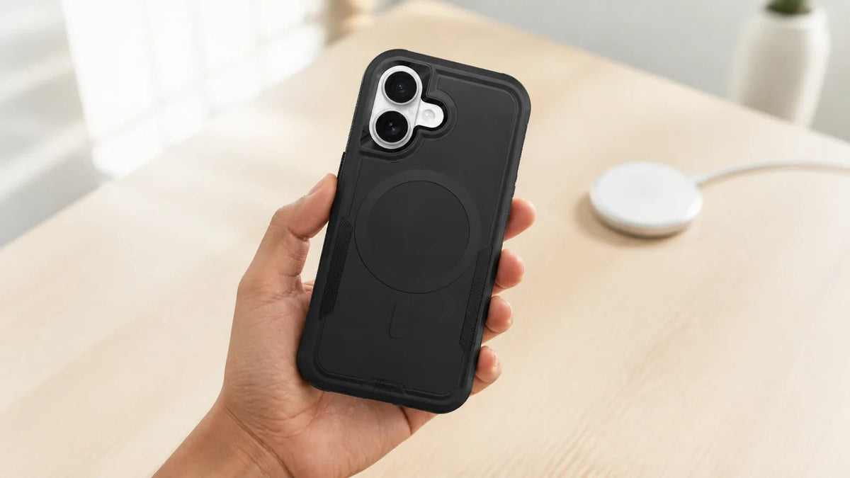 Mão segurando celular com capa Commander preta próxima a carregador magnético